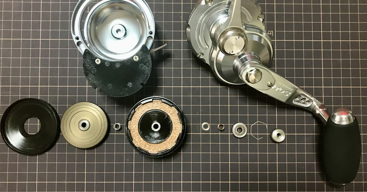 釣り用スピニングリールのハンドルノブ付け根に注油する手元のクローズアップ